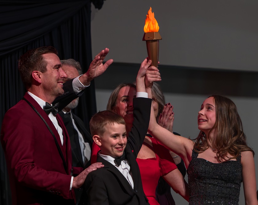Group of six people holding up lit torch.